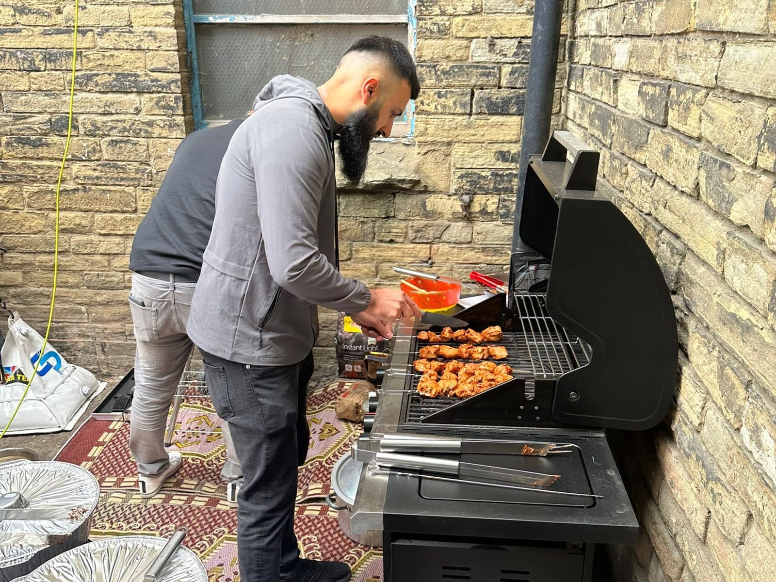 A volunteer cooking at the grill beside the dergah.