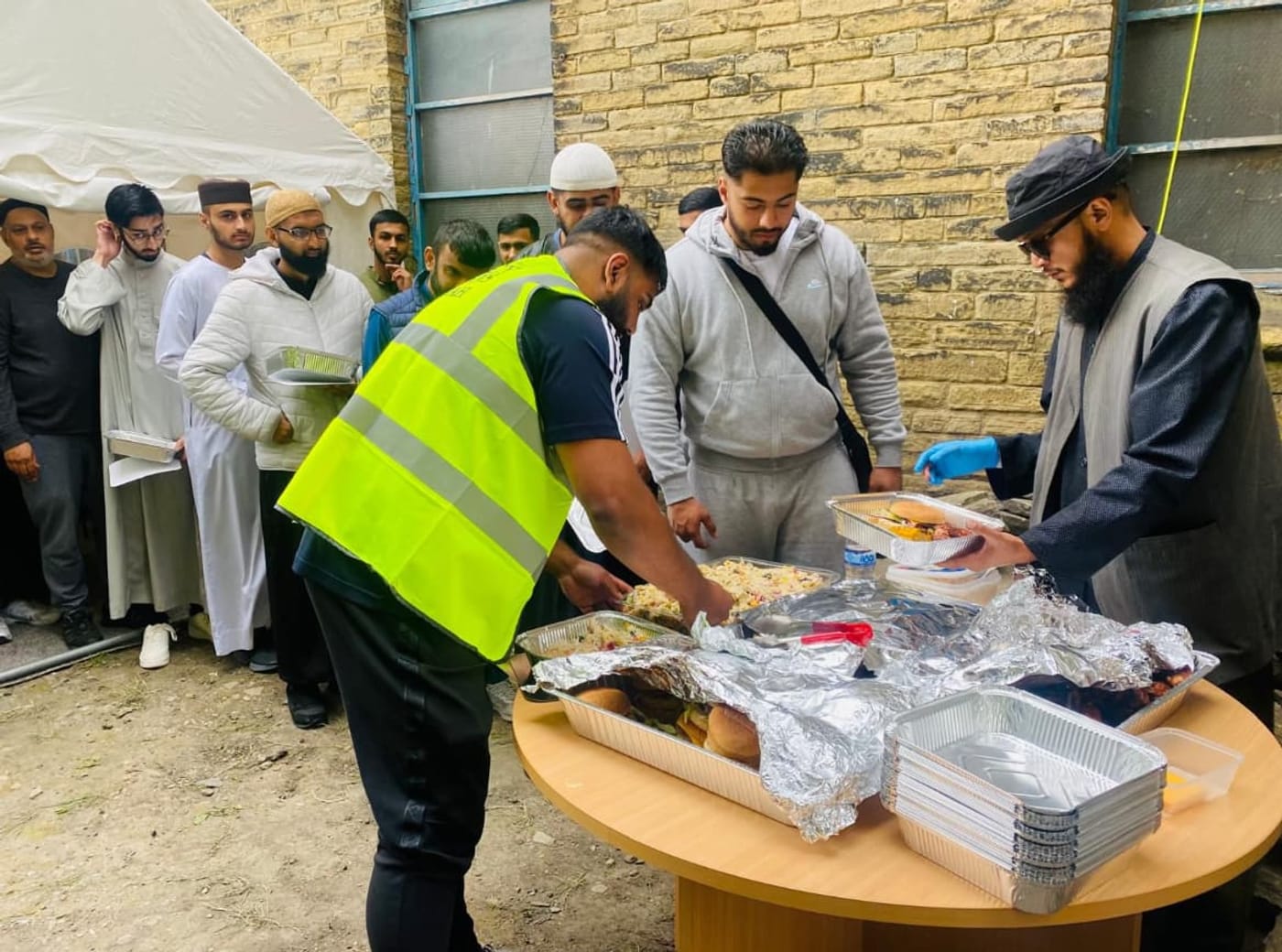 Volunteers serving food from the table outside the dergah.